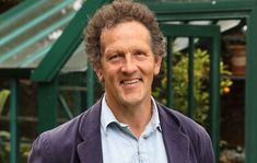 a man standing in front of a green house smiling at the camera with his hands on his hips