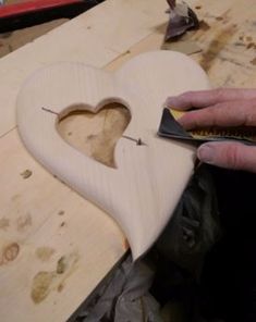 a heart shaped wooden object being worked on by a person using a wood planer