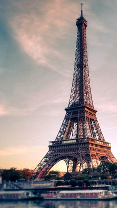 the eiffel tower in paris, france is lit up at sunset with boats passing by