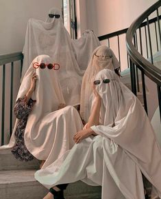 two women dressed in white sitting on the steps with their heads covered by veils