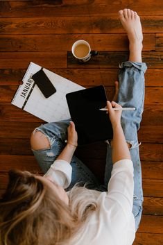 a woman is sitting on the floor with her laptop and coffee in front of her