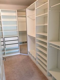 an empty walk in closet with white shelving