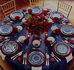 the table is set with blue and white plates, red napkins, and flowers