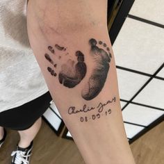 a person with a tattoo on their arm that has a baby's hand and foot prints