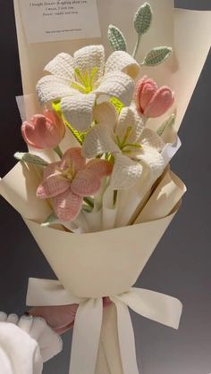 a bouquet of white and pink flowers in a paper wrapper next to a card