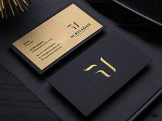 a black and gold business card sitting on top of a desk next to a feather