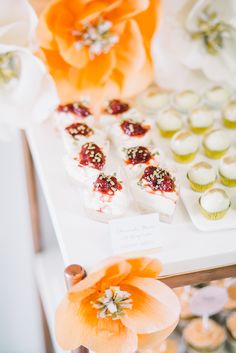 cupcakes are arranged on a table with orange flowers