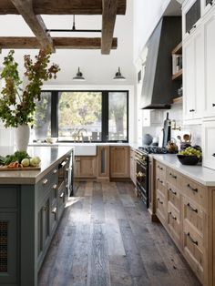 a large kitchen with wooden floors and white walls, along with an island in the middle