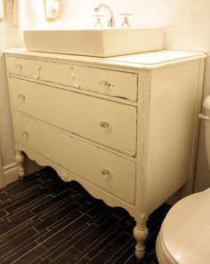 a bathroom with a toilet, sink and dresser