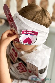 a young boy wearing a blindfold and holding up a pair of skis to his face