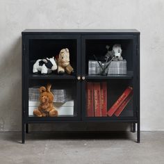 a bookcase with stuffed animals and books on it, against a concrete wall background