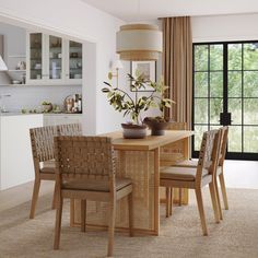 a dining room table with four chairs and a vase on the table in front of it