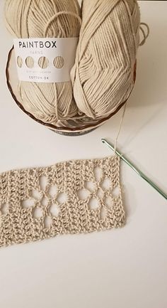 two balls of yarn sitting on top of a table next to a crochet doily