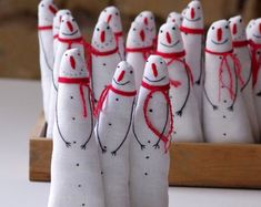 several white snowmen are lined up in a row on a wooden stand with red string