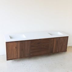 two white sinks sitting on top of a wooden cabinet in front of a white wall