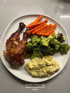 a white plate topped with chicken, carrots and broccoli covered in sauce