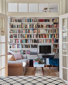 a living room filled with furniture and lots of books on the shelves in front of a flat screen tv