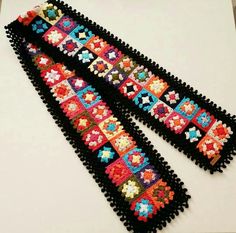 two black crocheted ties with colorful designs on them sitting next to each other