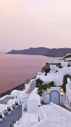 an outdoor dining area overlooking the ocean at dusk, with tables and chairs set out on the terrace