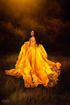 a woman in a yellow dress standing in tall grass