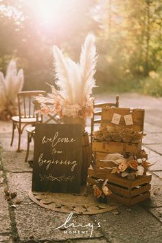 an outdoor ceremony setup with flowers, feathers and wooden crates on the ground in front of chairs