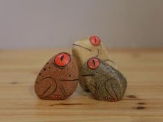 two rocks with faces painted on them sitting on a wooden table next to each other