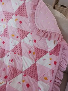 a pink and white quilt on top of a couch