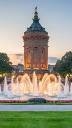 a fountain in front of a tall building with a clock on it's top