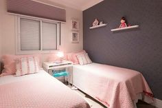 two twin beds in a small room with pink and white bedding on the walls