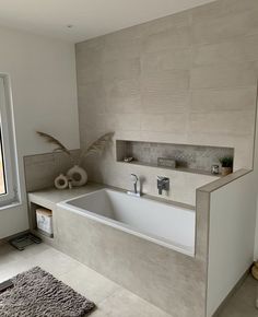 a bathroom with a large bathtub next to a window and rug on the floor