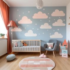 a baby's room with blue walls and clouds painted on the wall