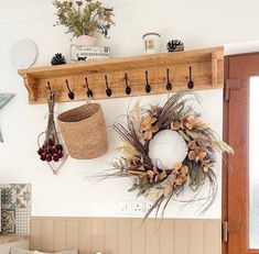 a wall mounted shelf with a wreath and two baskets on it next to a door