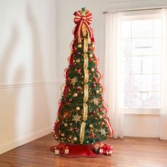 a decorated christmas tree with red and gold ribbons on it in front of a window