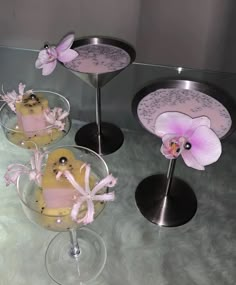 three desserts in glass dishes with pink flowers on the top and one is decorated like a bird