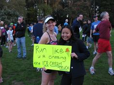 two women holding up a sign in front of a group of people on the grass