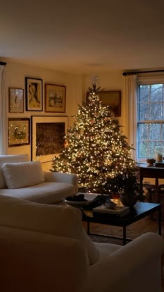 a living room filled with furniture and a lit christmas tree in the middle of it