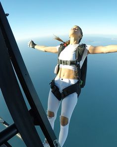 a woman is in the air with her arms spread out and she is wearing safety gear