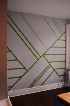 an empty room with green lines painted on the wall and wood table in front of it