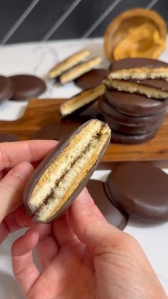 a hand holding an oreo cookie with chocolates in the back and on the side