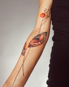 a woman's arm with a bird and flower tattoo on the left inner arm