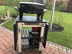 a bbq grill sitting on top of a wooden table next to a brick walkway