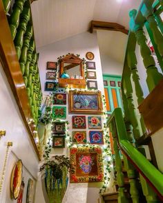 there are many framed pictures on the wall above the stair case and in the hallway