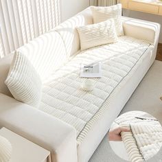 a living room with a white couch and pillows on the floor next to a coffee table