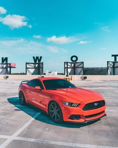 an orange mustang parked in a parking lot with the word world on it's side