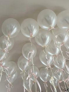 white balloons with pink ribbons and bows hanging from the ceiling