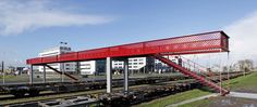 a red bridge over train tracks next to a building