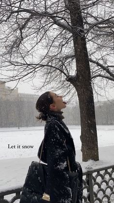 a woman standing in front of a tree on a snowy day with the words let it snow