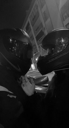 two people in helmets on a motorcycle at night