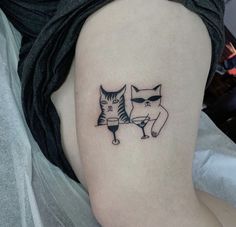 a couple of cats sitting next to each other on a woman's thigh,