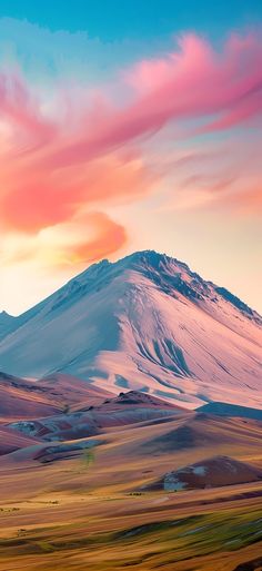 a mountain covered in snow under a colorful sky with clouds and grass on the ground